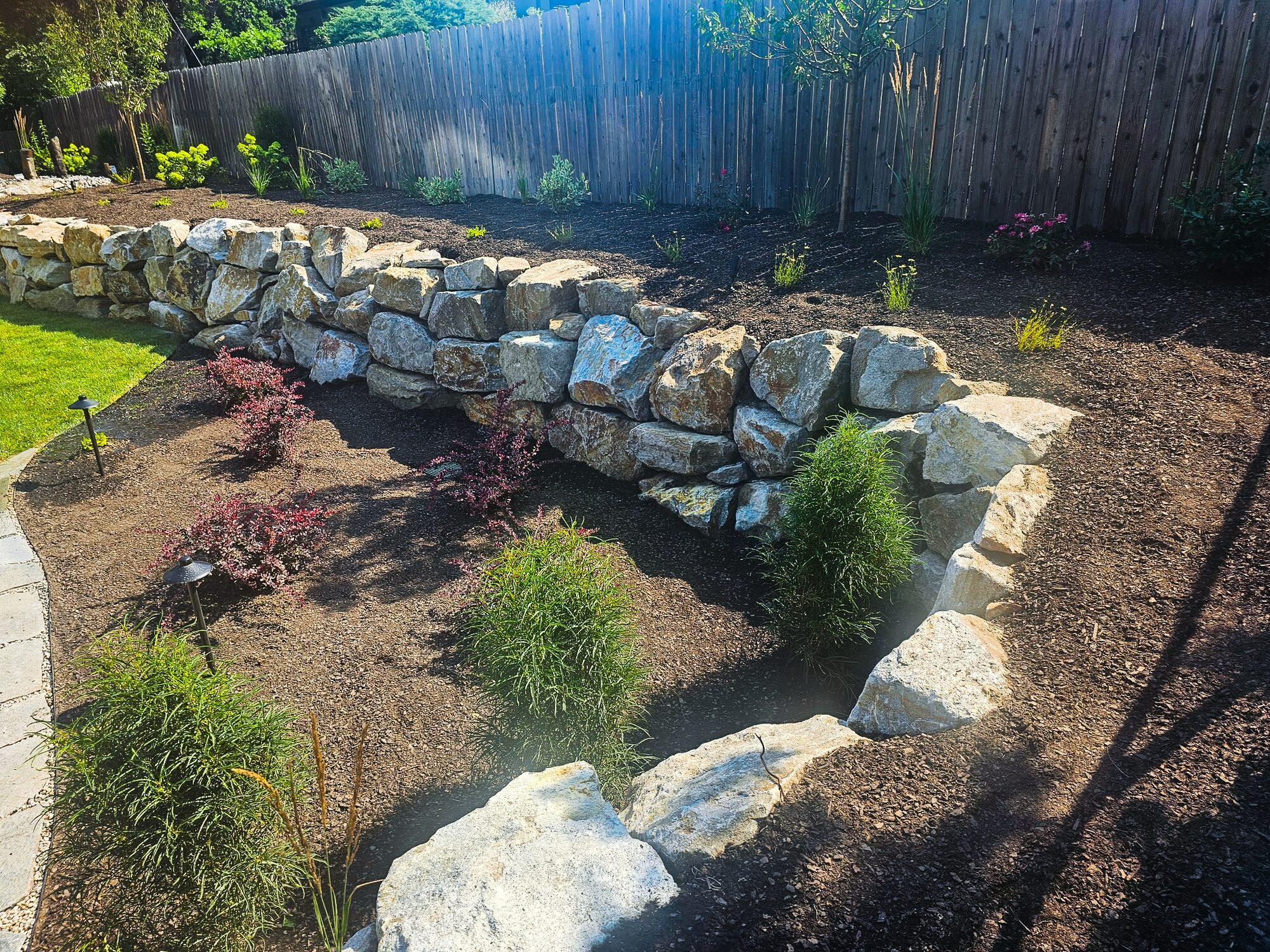 Boulder retaining wall with raised garden beds